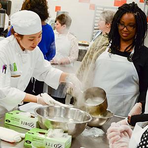 Women and chef looking over food preparations